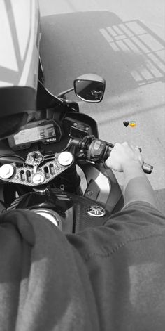 black and white photograph of person on motorcycle with yellow marker in the road next to it