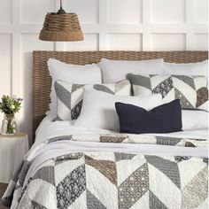 a bed with white sheets and pillows on top of it next to a basket lamp