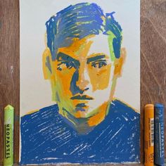 a drawing of a man's face is shown next to some crayons