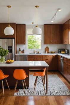 a kitchen with wooden cabinets and white counter tops, two orange chairs in front of an island