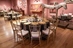 a room filled with tables and chairs covered in black table cloths next to a horse statue