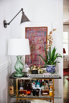 a bar cart with liquor bottles and plants on it