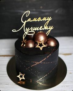 there is a black cake with gold stars on it and some chocolate balls in the middle