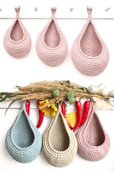 four crocheted vases hanging on a wall with flowers in the foreground