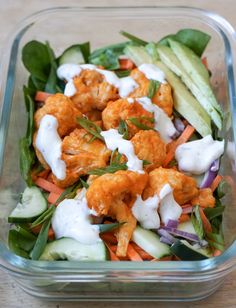 a salad with carrots, cucumbers and dressing in a glass dish on a wooden table