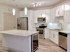 an empty kitchen with stainless steel appliances and white cabinetry is pictured in this image