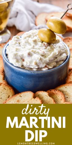 a bowl of dip with olives and crackers on the side