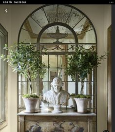 a statue sitting on top of a table with potted plants in front of it