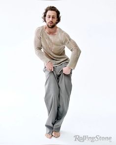 a man with his hands on his hips posing for the camera while wearing grey pants