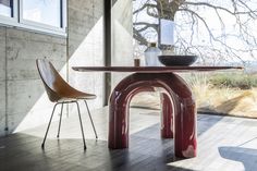 a table and chair sitting on top of a hard wood floor next to a window