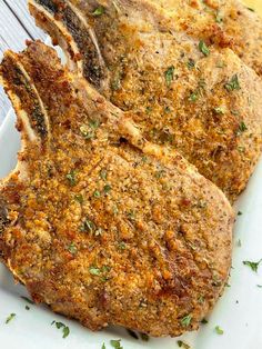 three pieces of meat on a white plate with parsley sprinkled on top