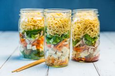 three mason jars filled with different types of food and chopsticks next to each other