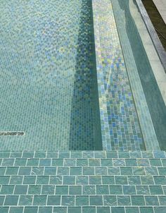 an empty swimming pool with tiled walls and steps