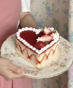 a woman holding a heart shaped cake with strawberries on top and whipped cream in the middle