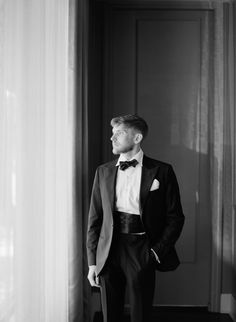 a man in a tuxedo standing next to a door