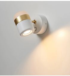 a white wall light with a gold trim on the front and back of it's head