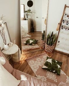 a mirror sitting on top of a wooden floor next to a plant in a vase