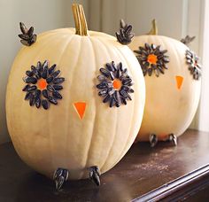 two white pumpkins decorated with black and orange flowers on top of a wooden table