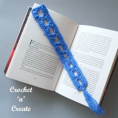 an open book with a blue crochet tassel on it