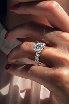 a woman's hand with a ring on her finger and a diamond in the middle