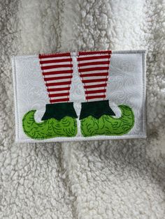 a patch with two legs in the shape of a pair of boots on top of a white blanket