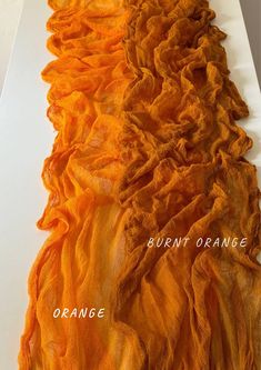 an orange scarf is laying on a white surface with the words burnt orange above it