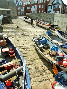 there are many small boats parked on the shore next to each other in front of houses