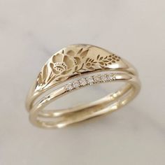 two wedding bands with flowers and leaves on them, one is yellow gold the other is white diamonds