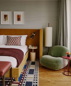 a bed sitting in a bedroom next to a green chair and table on top of a hard wood floor