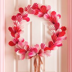 a wreath made out of pink paper sitting on top of a door