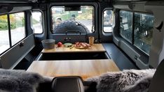 an interior view of a camper van with wood tables and benches in the foreground