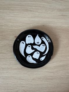 a black and white plate with ghost faces painted on the side, sitting on a wooden surface