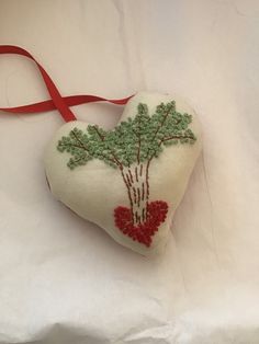 a heart shaped ornament decorated with green and red flowers on a white background