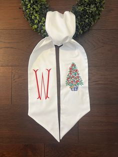 a white neck tie with a christmas tree on it and the letter w in red