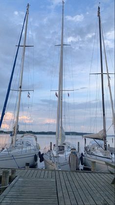 several sailboats docked at a pier on the water