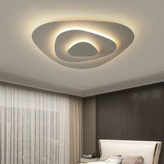 a bed room with a neatly made bed and a round light above the headboard