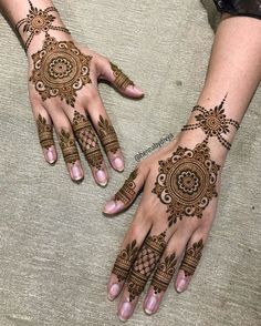 two hands with henna tattoos on them, one is showing off the intricate design