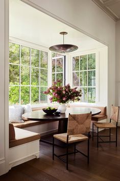 a dining room table with two chairs and a vase filled with flowers on top of it