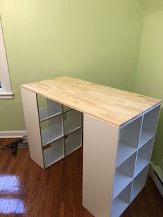 an empty room with a wooden desk and shelving unit on the floor, in front of a green wall