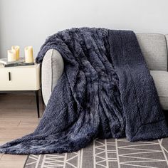 a living room with a couch, chair and rug covered in a dark blue blanket