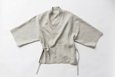 an unisex white kimono is shown on a white surface with no one around it