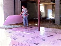 a man standing next to a pink couch on top of a hard wood floor in an unfinished room