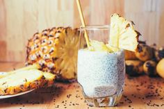 a pineapple is next to a glass of chia seed pudding with a straw in it