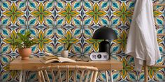 a table with a lamp and a book on it in front of a patterned wall