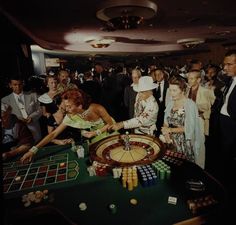 a group of people standing around a rouleette in a room full of other people