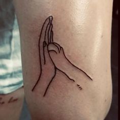 a small tattoo on the leg of a person holding their hands up to show that they are praying