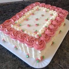 a square shaped cake with pink frosting roses on it sitting on a counter top