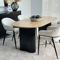 a dining room table with chairs and a bowl on it's centerpiece in front of a window