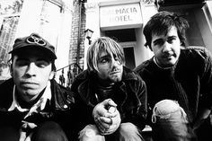 three young men sitting on steps in front of a hotel