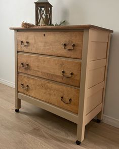 a wooden dresser sitting on top of a hard wood floor next to a white wall